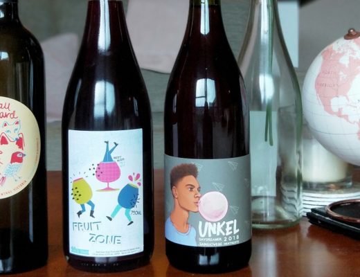 three natural wine bottles in a row on table