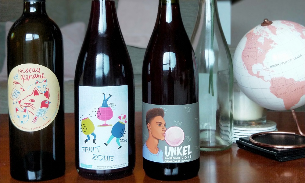 three natural wine bottles in a row on table
