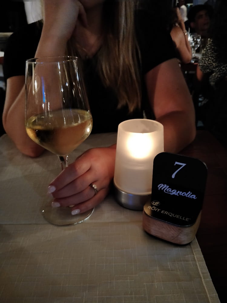 woman at dinner table holding white wine in glass with candle