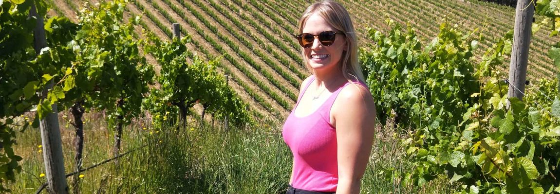 blonde woman in pink top standing in basket range vineyard