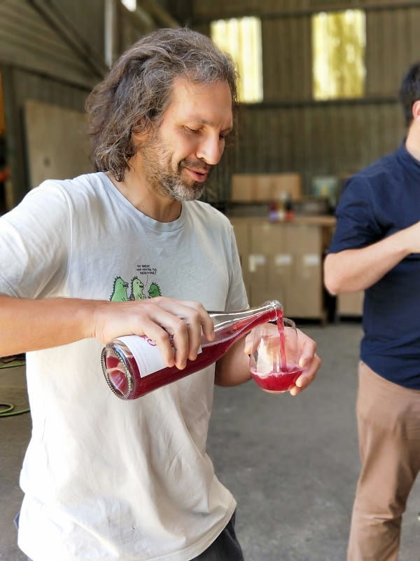 alex schulkin the other right winemaker pouring red wine in to glass