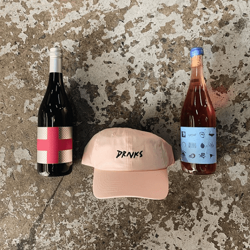 drnks wine delivery service wine bottles on floor with pink cap that says drnks on it