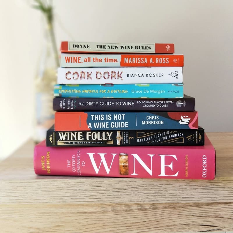 christmas gift guide wine books stacked in a pile on wooden surface