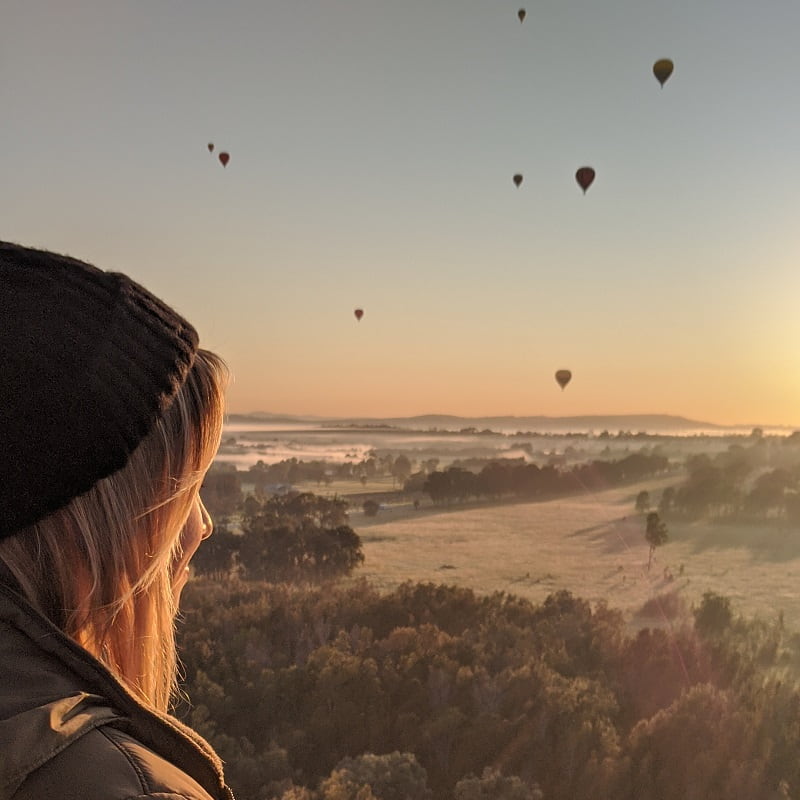 christmas gift guide woman overlooking hunter valley vineyards with hot air balloons in sky